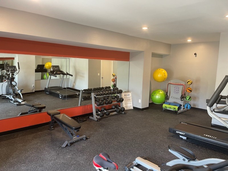 a room with a lot of exercise equipment and a yellow ball in the corner